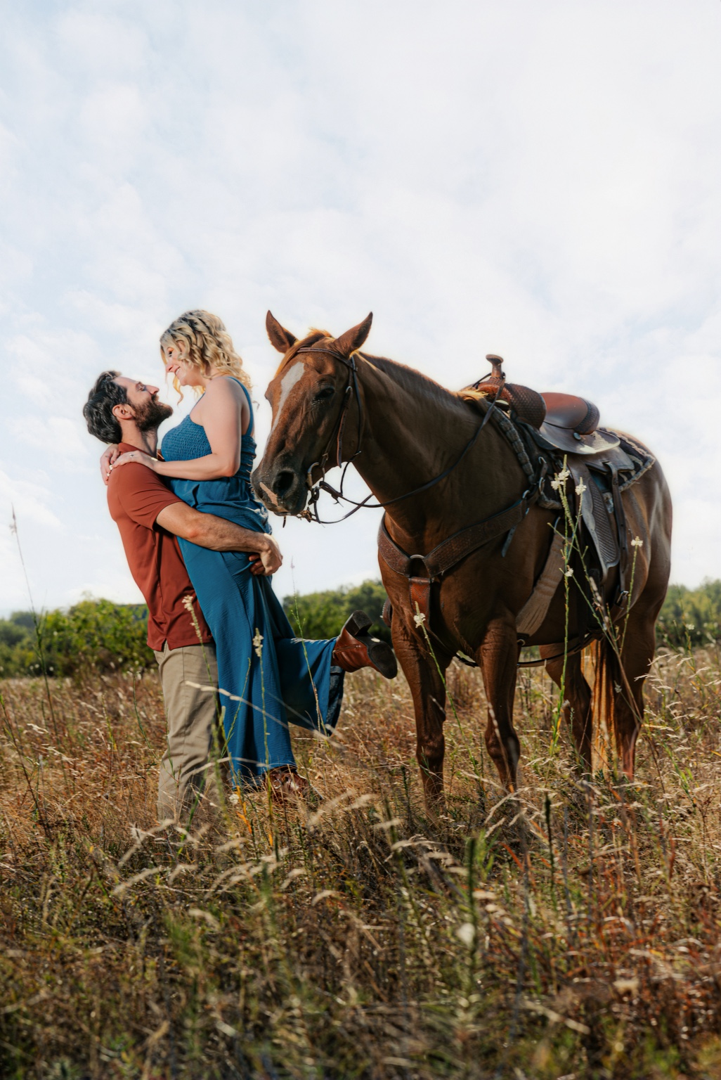 Engaged couple sharing a playful lift beside a horse in Dallas