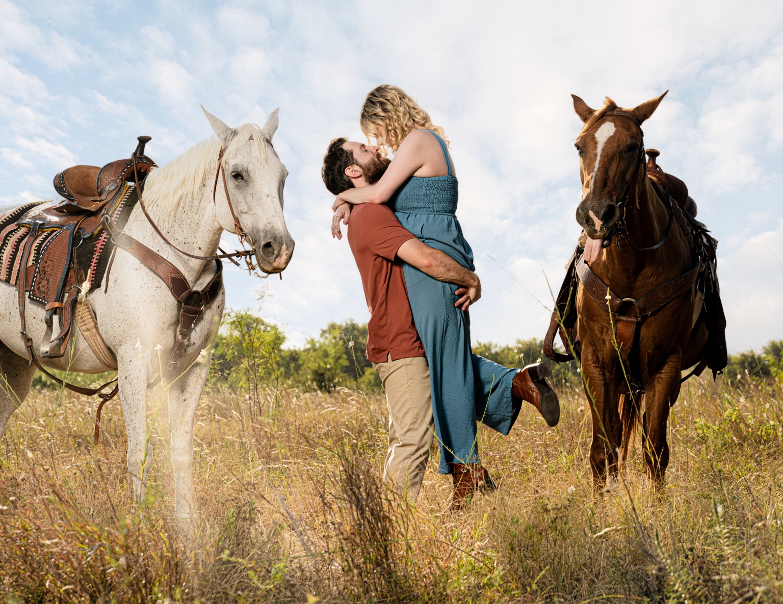 Couple kissing between two horses during a Dallas ranch engagement session