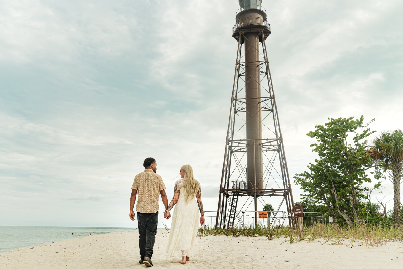 Engaged couple walking beside a Florida beach lighthouse