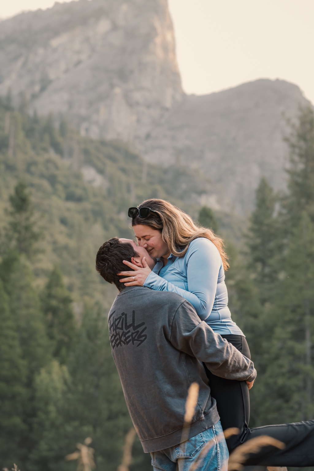 Engaged couple kissing beneath Yosemite granite peaks
