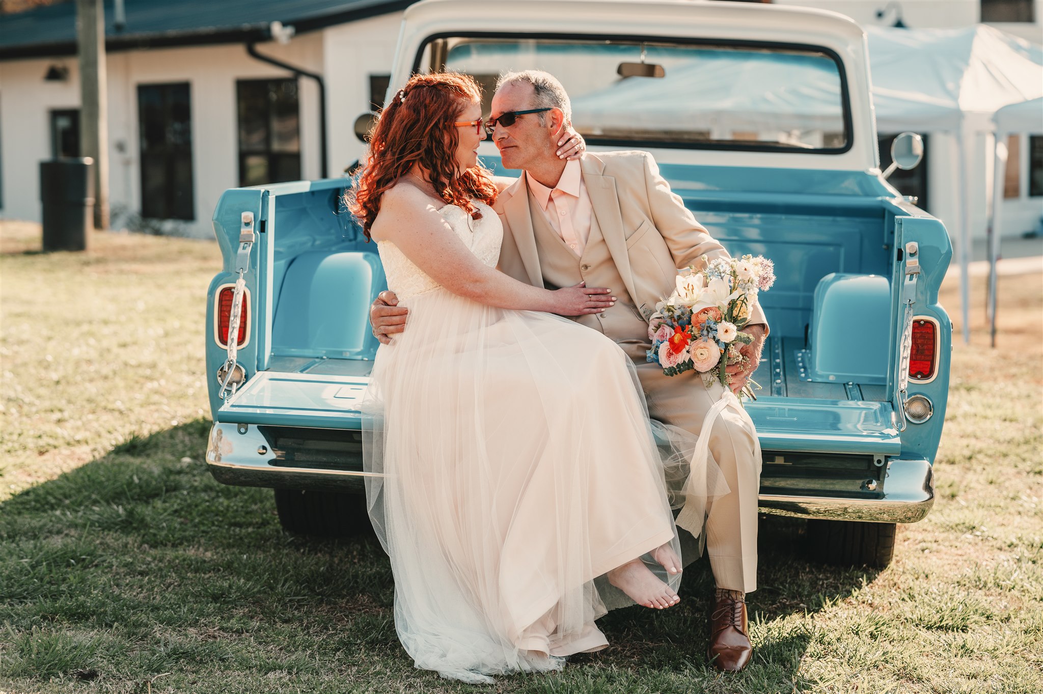 Newlyweds sharing a portrait in the bed of a vintage blue truck